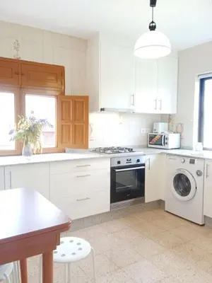 a kitchen with white cabinets and a washer and dryer at Casa Calvo in Vivero