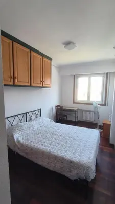 a bedroom with a bed and wooden floors and cabinets at Pirámides Ourense in Ourense
