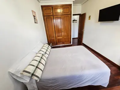 a bedroom with a white bed with a wooden door at Pirámides Ourense in Ourense