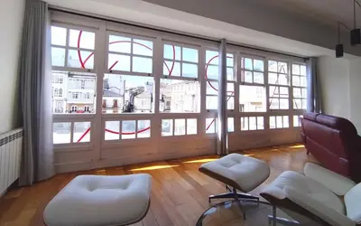 a living room with a large window and white chairs at Arq Plaza Mayor in Viveiro