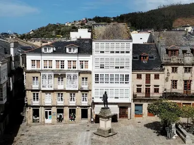 a large white building with a statue in front of it at Arq Plaza Mayor in Viveiro