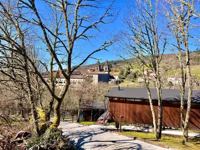 a barn with a building in the background with trees at Casal Oseira in Ourense