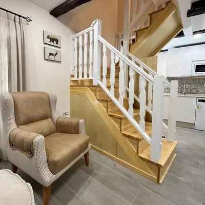 a living room with a staircase and a chair at Casa la florida in Puebla de Sanabria