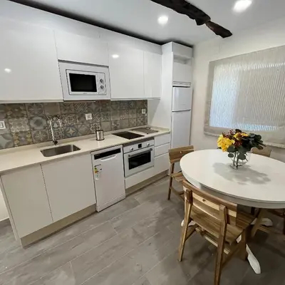 a kitchen with white cabinets and a table with a vase of flowers at Casa la florida in Puebla de Sanabria