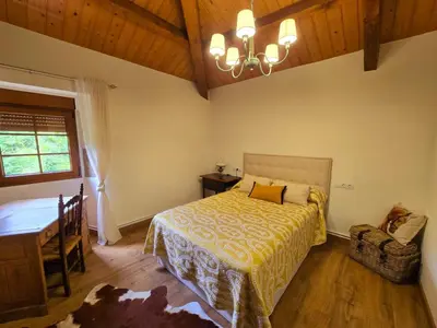 a bedroom with a bed and a table and a chandelier at PORTA ESPERANZA in Cospeito