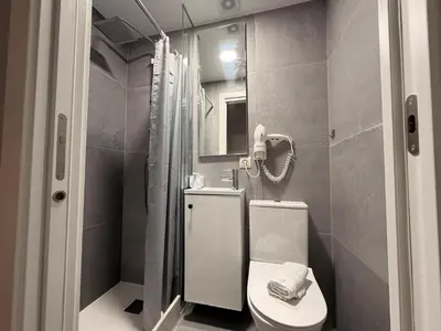 a bathroom with a toilet and a bedroom with a bed at O Loureiro - Grupo Arcanos in Caldas de Reis