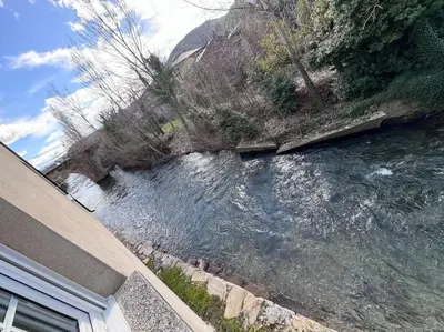a river next to a house next to a hill at La Puerta del Valle in Villafranca del Bierzo