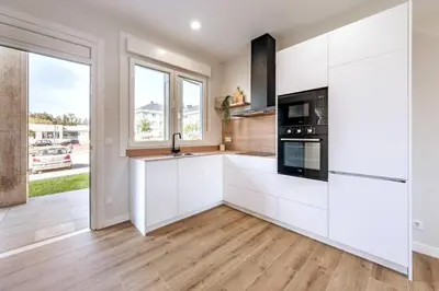 a kitchen with white cabinets and black appliances at White Tree Rooms and Apartments in O Pedrouzo