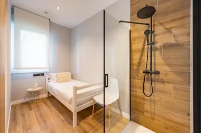a small bedroom with a bed and a shower at White Tree Rooms and Apartments in O Pedrouzo