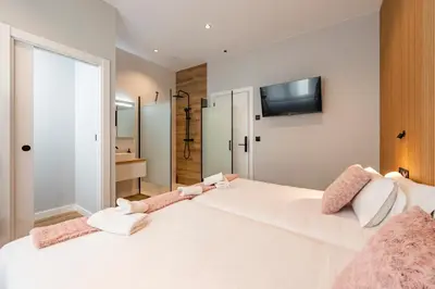 a bedroom with a large white bed with a tv on the wall at White Tree Rooms and Apartments in O Pedrouzo