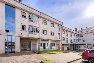 an apartment building with a car parked in a parking lot at White Tree Rooms and Apartments in O Pedrouzo