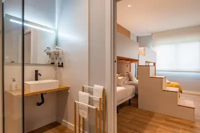 a bathroom with a sink and a bedroom at White Tree Rooms and Apartments in O Pedrouzo