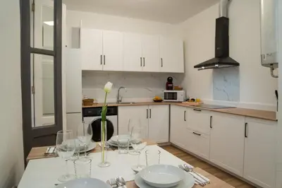 a kitchen with white cabinets and a table with wine glasses at Catapiro - Confort Elegante y Exclusivo en el Corazón de la Ciudad in Ourense