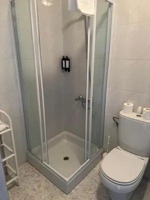 a shower with a glass door next to a toilet at Triacastela Sunset Terrace in Tríacastela