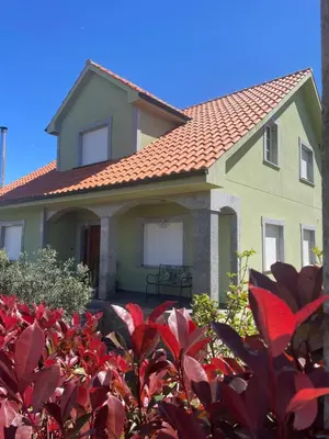 a house with a red bush in front of it at A Casa de Buxacos in Arzúa