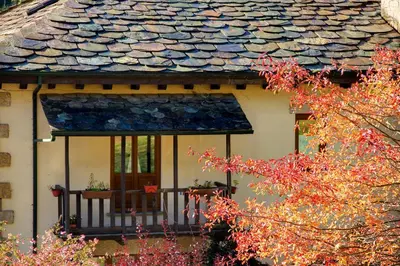 a house with a balcony and a roof at Hotel Balneario Río Pambre in Palas de Rei