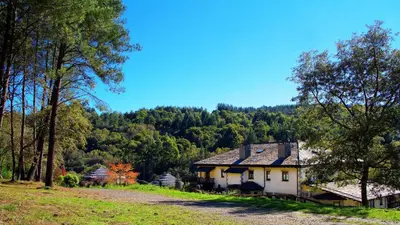 a house in the middle of a field with trees at Hotel Balneario Río Pambre in Palas de Rei