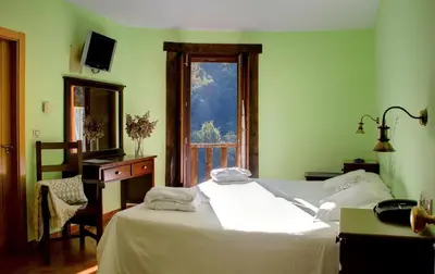a bedroom with two white beds and a window at Hotel Balneario Río Pambre in Palas de Rei