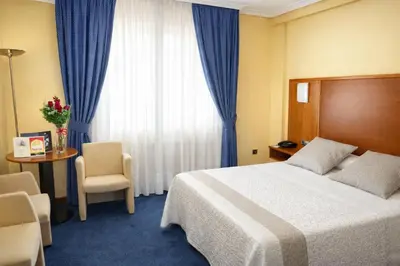 a hotel room with a bed and a table and a window at Motel Punta Cana in Santiago de Compostela