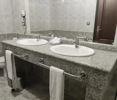 a room with a bed and a chair and a tv at Motel Punta Cana in Santiago de Compostela