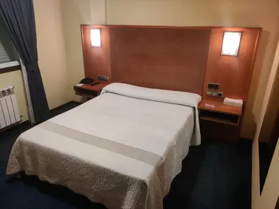 a room with a bed and a tv on a wall at Motel Punta Cana in Santiago de Compostela