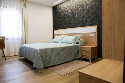 a bedroom with a bed and a wooden floor at A Quinta de Cea - Apartamentos in Cea