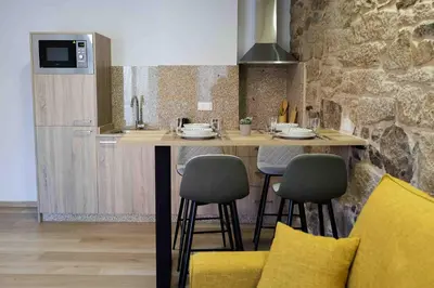a kitchen with a island with chairs and a counter top at A Quinta de Cea - Apartamentos in Cea