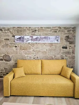 a yellow couch in front of a brick wall at A Quinta de Cea - Apartamentos in Cea