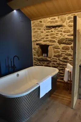 a bath tub in a bathroom with a stone wall at Cabana de Pili in A Estrada