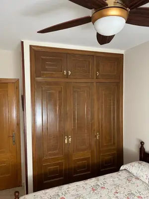 a bedroom with wooden cabinets and a ceiling fan at PENSIÓN* AS VIÑAS in Puebla del Brollón