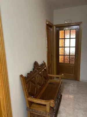 a wooden bench sitting in a room with a door at PENSIÓN* AS VIÑAS in Puebla del Brollón