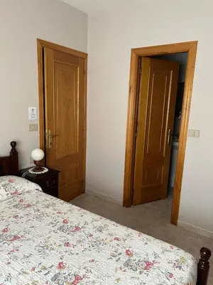 a bedroom with a bed and two wooden doors at PENSIÓN* AS VIÑAS in Puebla del Brollón