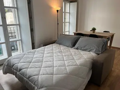 a bedroom with a large white bed and a table at Apartamento con Encanto in Santiago de Compostela