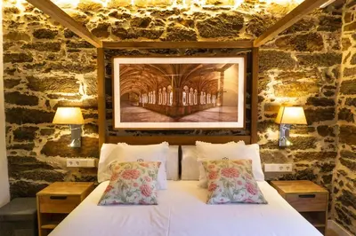 a bedroom with a white bed in a stone wall at Ribeira Sacra a Orilla Rio Miño Casas do Pincelo in Pincelo