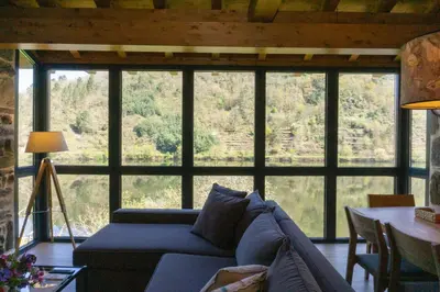 a living room with a blue couch in front of a large window at Ribeira Sacra a Orilla Rio Miño Casas do Pincelo in Pincelo