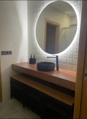 a bathroom with a sink and a round mirror at Apartamento en Barreiros in San Miguel de Reinante
