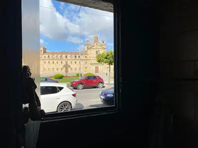 a window view of a building with cars parked in a parking lot at Campo de la Compañía in Monforte de Lemos