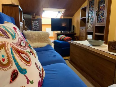 a living room with a blue couch and a tv at Duplex Casa Camino in Ponferrada
