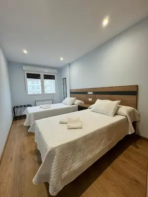 a room with three beds and a window at Cortiñas in Villalba