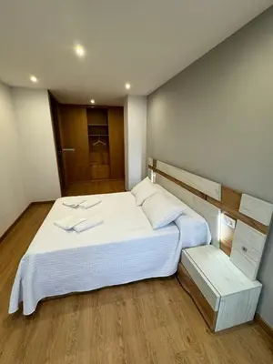 a bedroom with a large white bed and a wooden floor at Cortiñas in Villalba