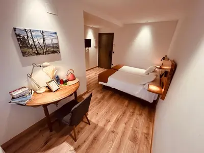 a small room with a bed and a desk with a table at A Reigada Hotel Restaurante in Grandas de Salime