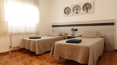 two beds in a room with a window at Pensión Albergue Gonzar in Portomarin