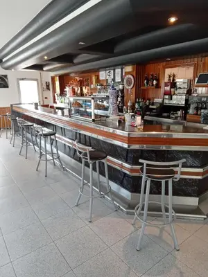 a bar with a row of stools in a restaurant at Pensión Albergue Gonzar in Portomarin