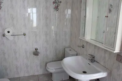 a bathroom with a white toilet and a sink at Pensión Albergue Gonzar in Portomarin