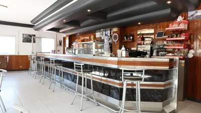 a bar in a restaurant with stools at Pensión Albergue Gonzar in Portomarin