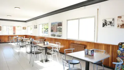 a restaurant with tables and chairs and windows at Pensión Albergue Gonzar in Portomarin