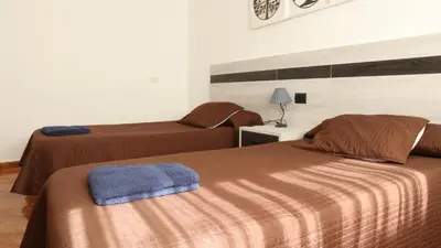 a hotel room with two beds with brown sheets at Pensión Albergue Gonzar in Portomarin