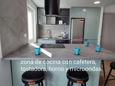 a kitchen with a counter with stools in it at O Paseo, 5 estrellas. in Puentedeume