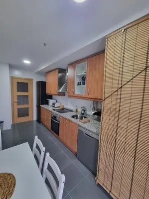 a kitchen with wooden cabinets and a table and chairs at El mirador del Rosal in Ponferrada