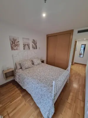 a bedroom with a white bed and a wooden floor at El mirador del Rosal in Ponferrada